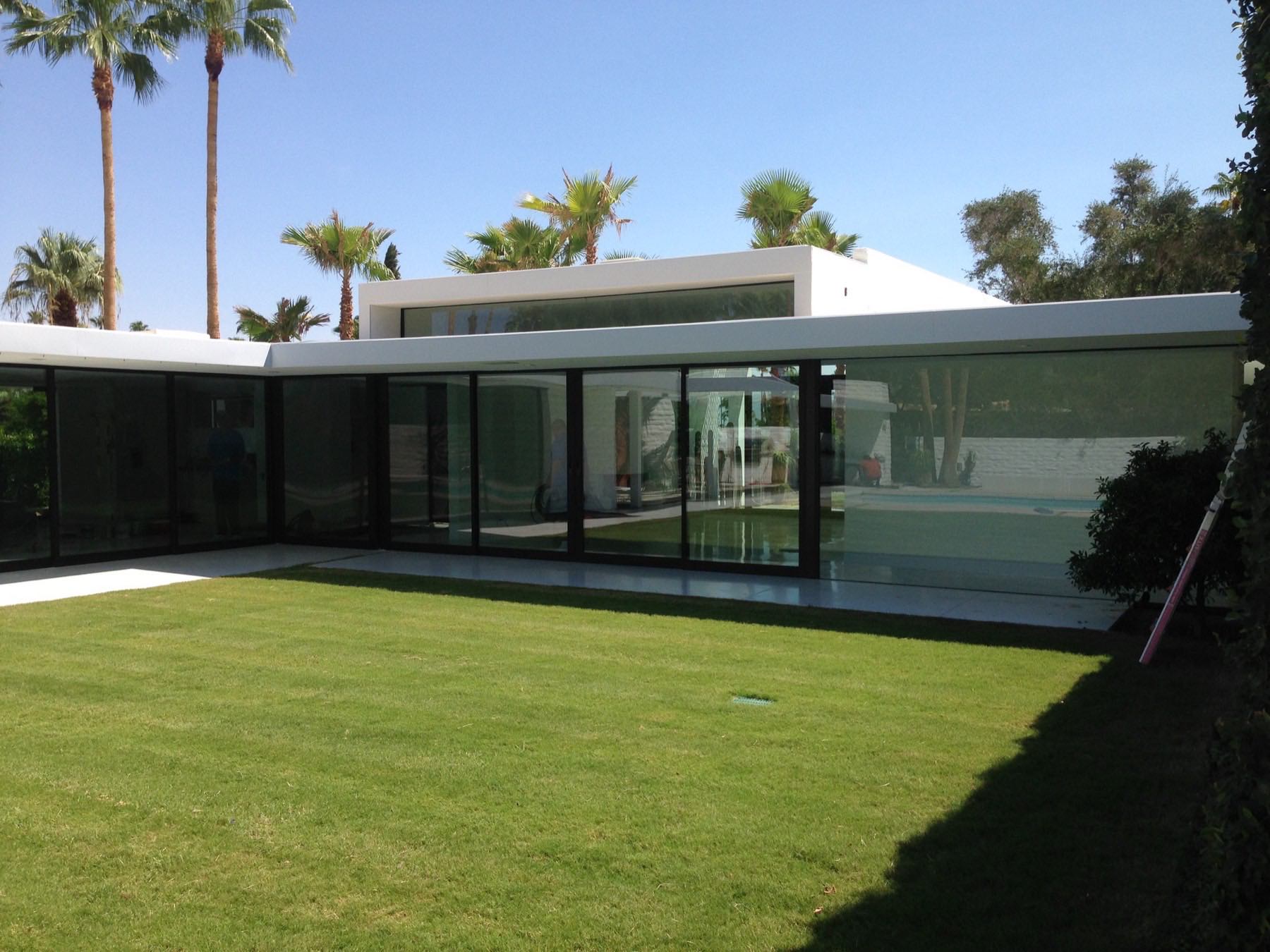 Desert estate home with floor-to-ceiling glass walls cleaned to a flawless shine, palms and pool reflected in the windows