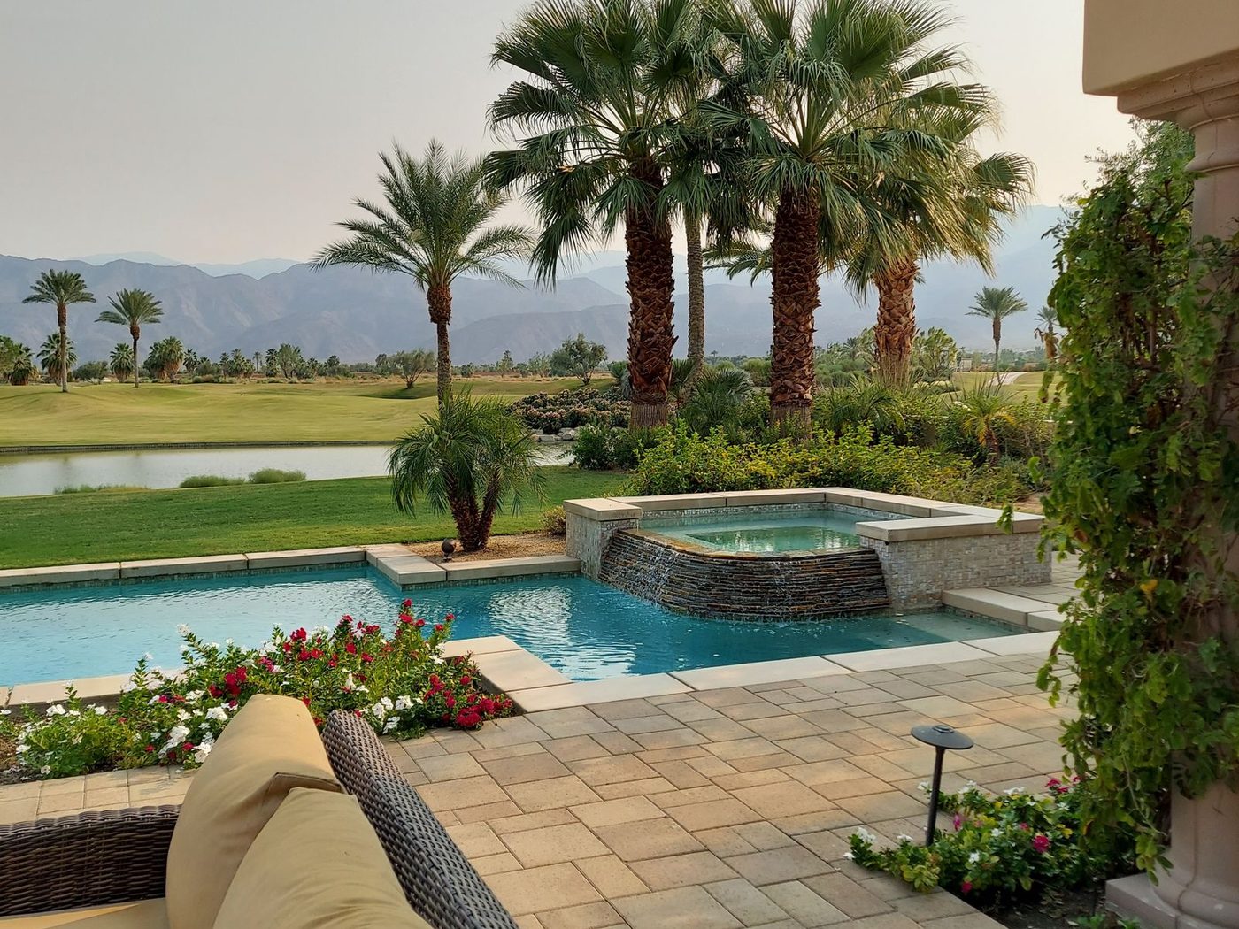 Paver pool deck and palms overlooking a Coachella Valley golf course with mountains beyond
